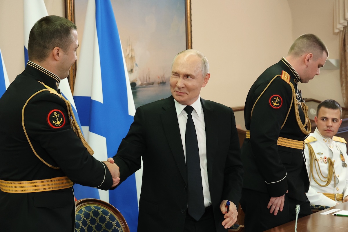Vladimir Putin fa l'occhiolino a un ufficiale russo mentre gli stringe la mano durante una cerimonia al Cremlino, il 26 luglio