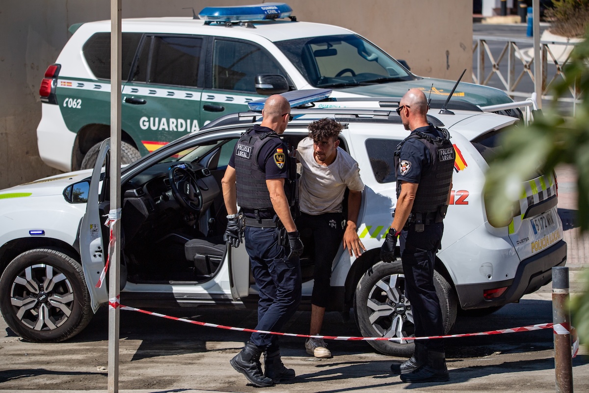 Alcuni poliziotti spagnoli insieme a una persona immigrata a Ceuta, il 2 agosto 2026 (AP/Antonio Sempere)