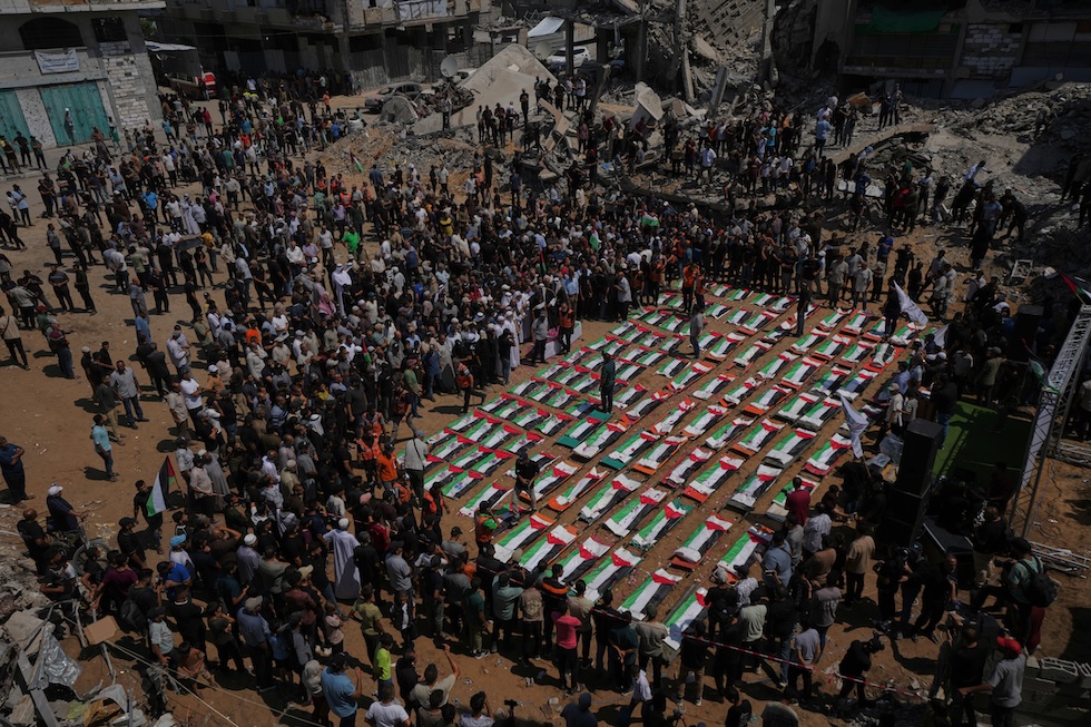 I corpi dei membri di due famiglie, uccisi in un attacco israeliano nel 2023 e recuperati solo recentemente dalle macerie, avvolti nelle bandiere palestinesi durante i funerali (AP Photo/Jehad Alshrafi)