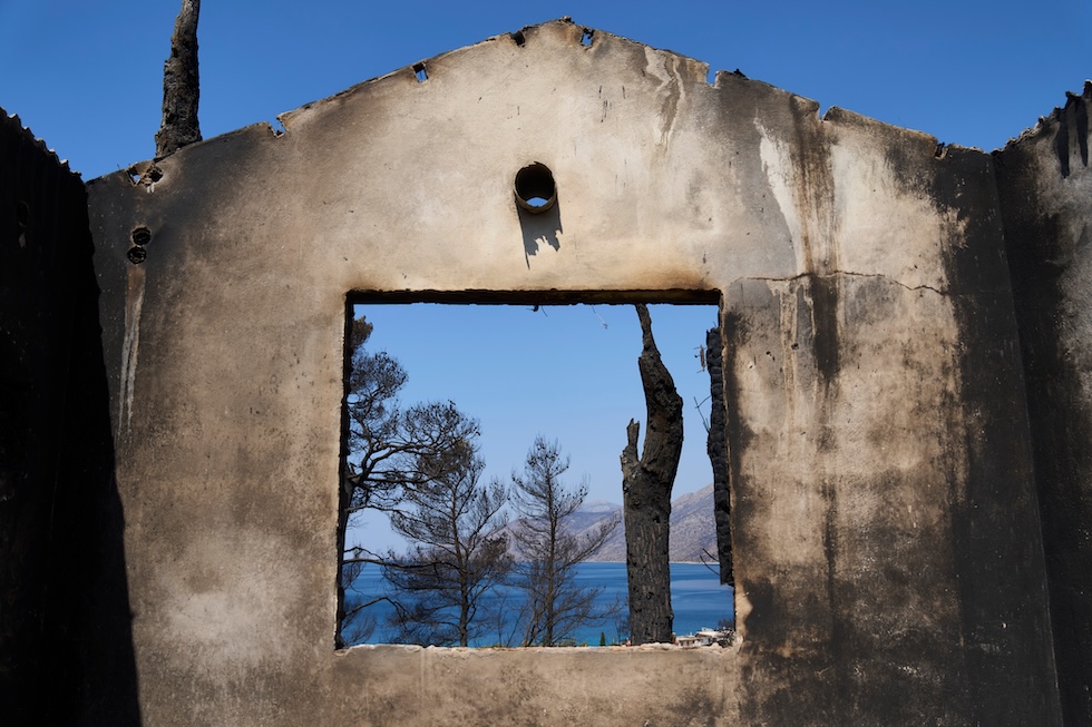 Il mare visto attraverso la finestra di una casa distrutta da un incendio, a nord-ovest di Atene (AP Photo/Petros Giannakouris)