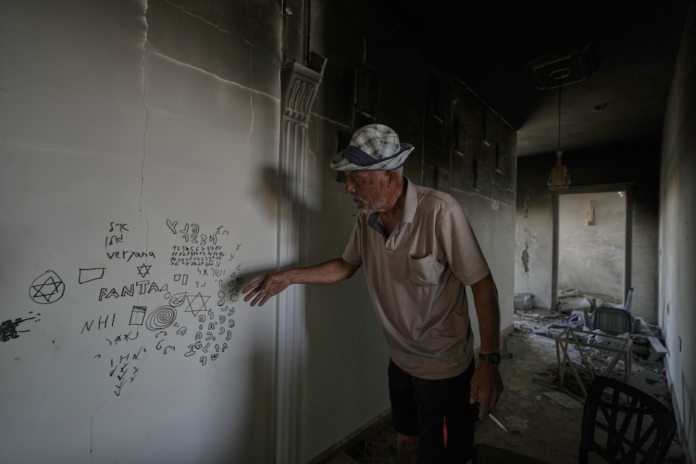 Un uomo libanese mostra alcune scritte in ebraico lasciate dai soldati israeliani nella sua casa, distrutta durante le operazioni militari israeliane nel sud del Libano (AP Photo/Mohammed Zaatari)
