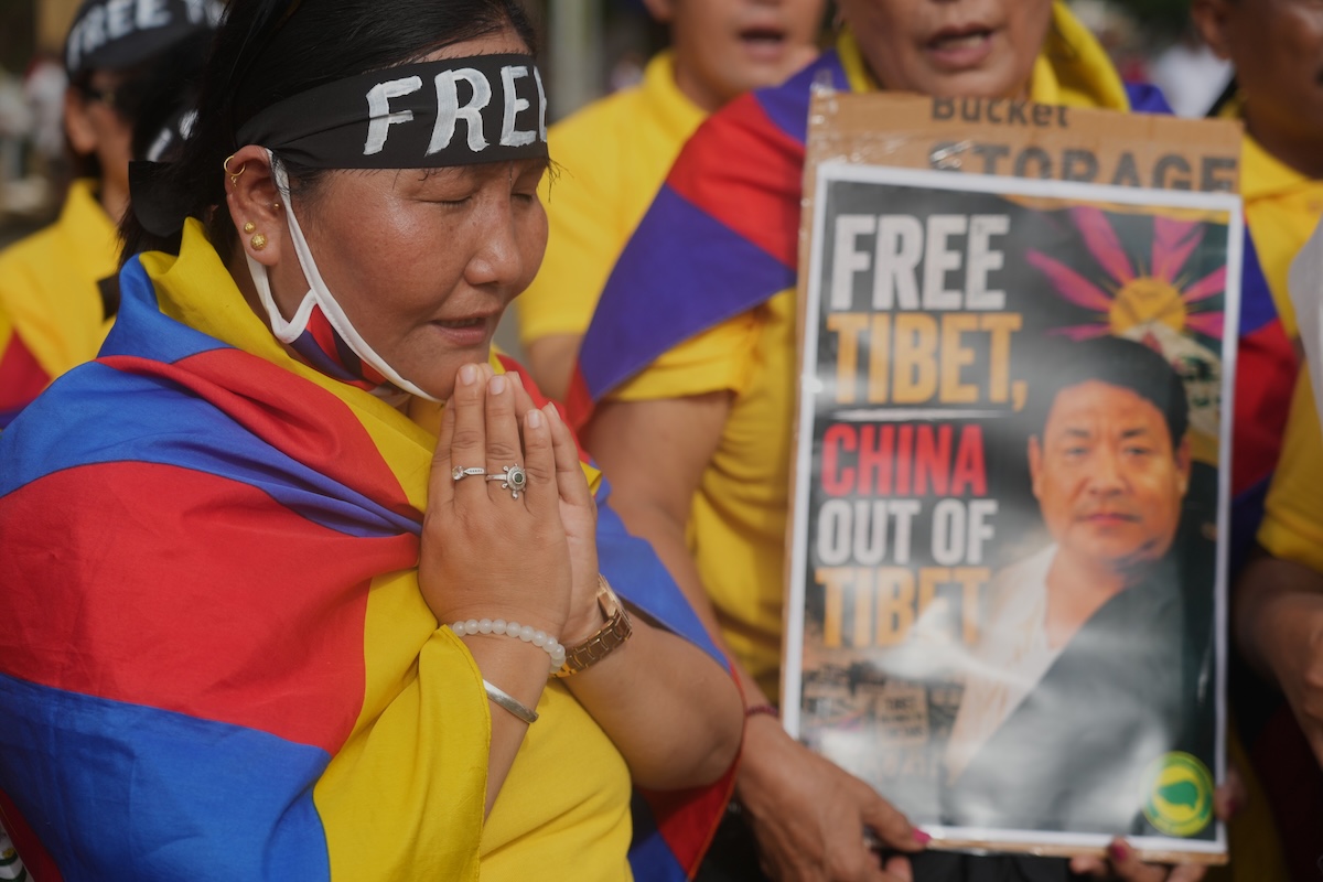 Alcuni manifestanti tibetani a una protesta contro la Cina, con un ritratto di Lobga Rangzen, a Mumbai, il 2 agosto 2026 (AP/Rafiq Maqbool)