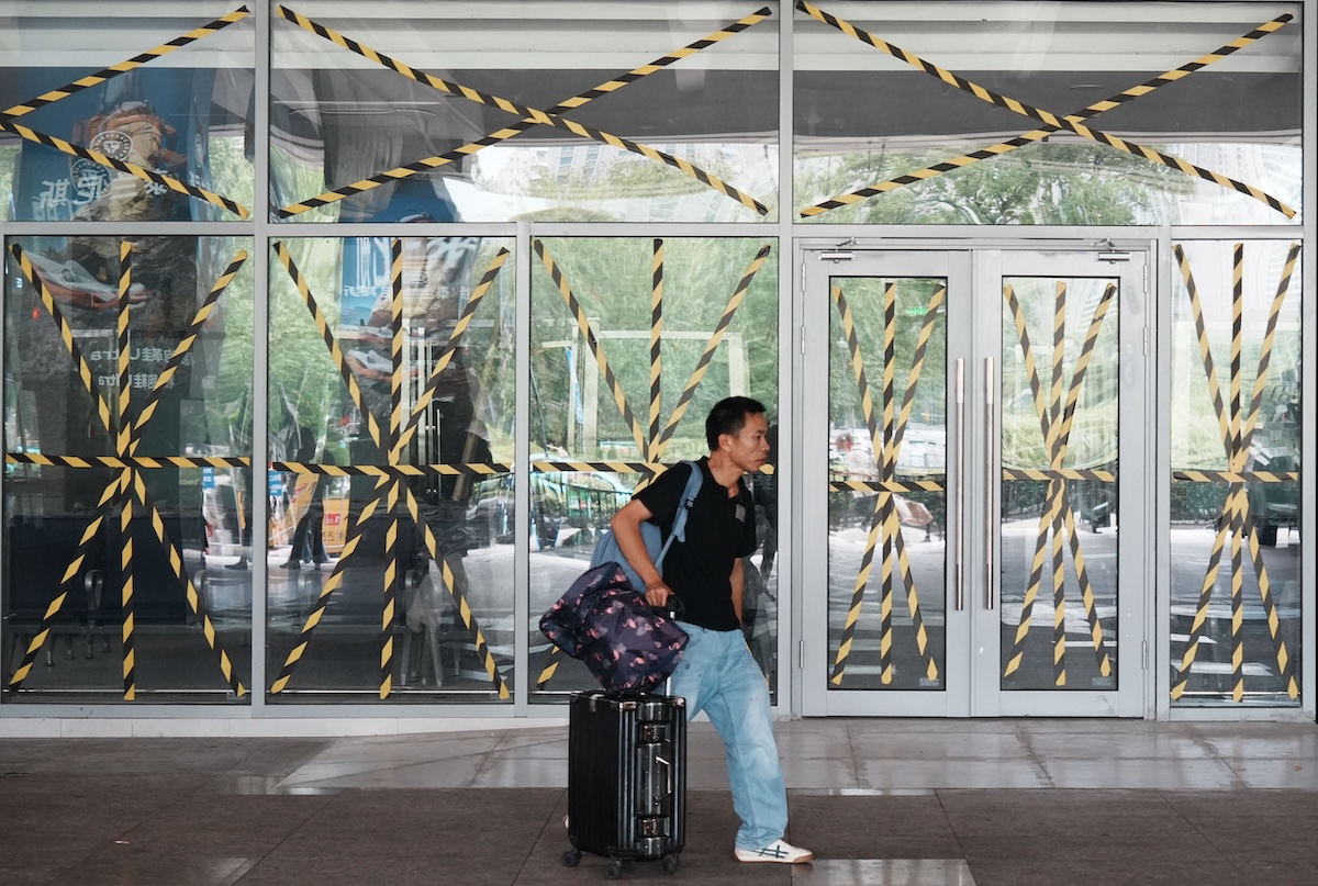 Un uomo davanti alle vetrate di una stazione dei bus protette in attesa dell'arrivo del tifone Dolphin (Chinatopix Via AP)
