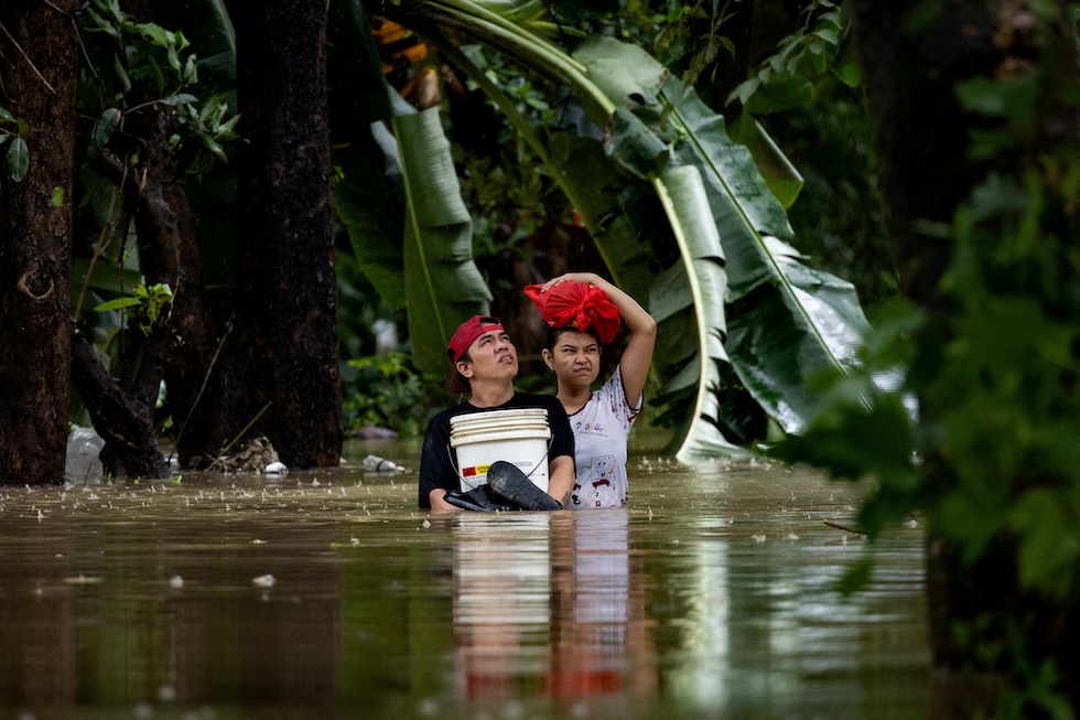 Due persone in una strada allagata dalle piogge monsoniche nella zona di Bagong Silangan (REUTERS/Eloisa Lopez)
