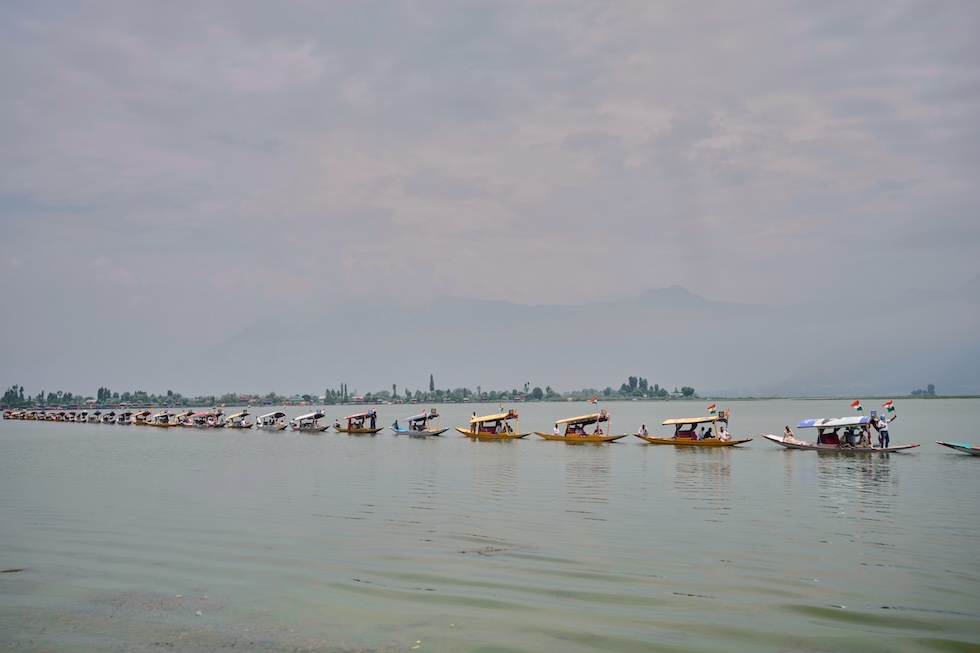 Una fila di shikara, tipiche imbarcazioni in legno del lago Dal, durante una manifestazione in barca dei sostenitori del Bharatiya Janata Party (BJP), il partito nazionalista, induista e di destra guidato dal primo ministro Narendra Modi, in vista delle celebrazioni per l’indipendenza dell’India dal Regno Unito (AP Photo/Mukhtar Khan)
