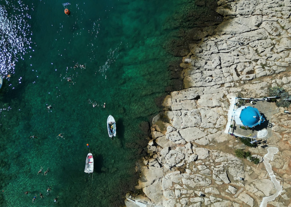 Bagnanti al mare vicino alla cappella di Agios Nikolaos, nel porto del Pireo (AP Photo/Thanassis Stavrakis)
