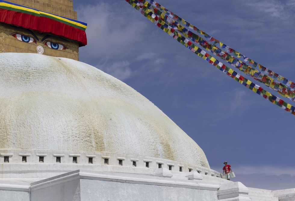 Una persona allo stupa di Boudhanath per dipingere (EPA/NARENDRA SHRESTHA)