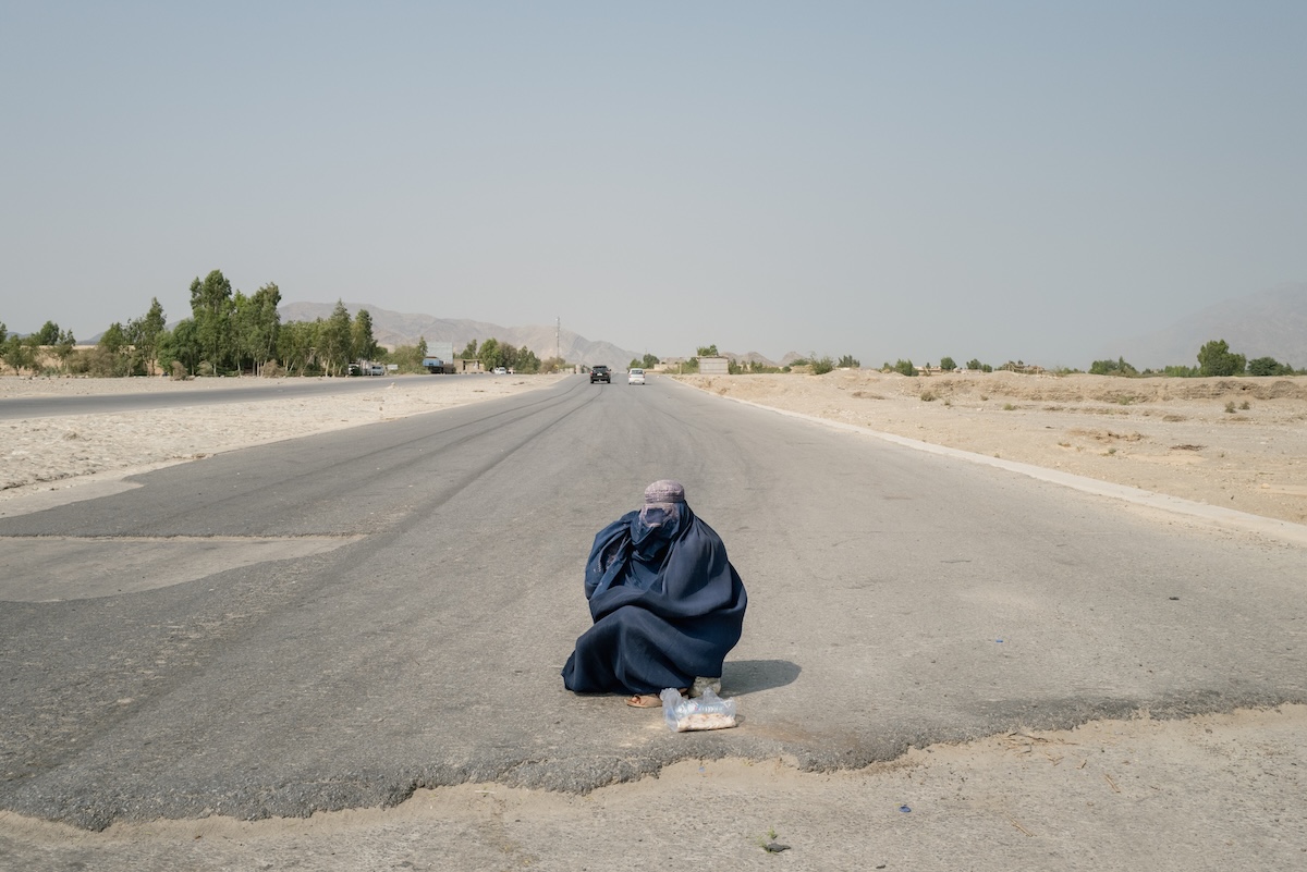 Una donna fa l'elemosina per strada a Torkham, in una foto del settembre 2025