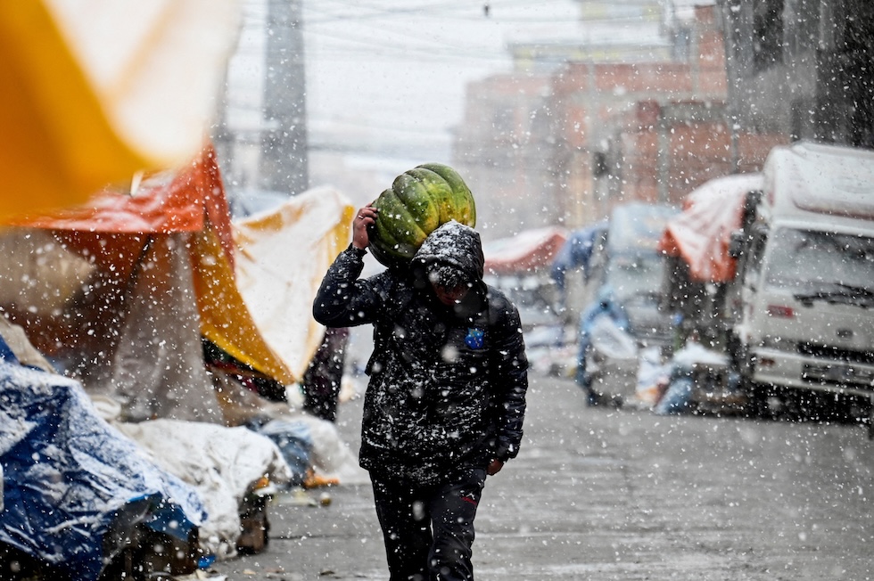 Una persona cammina sotto la neve trasportando una zucca sulle spalle (REUTERS/Claudia Morales)