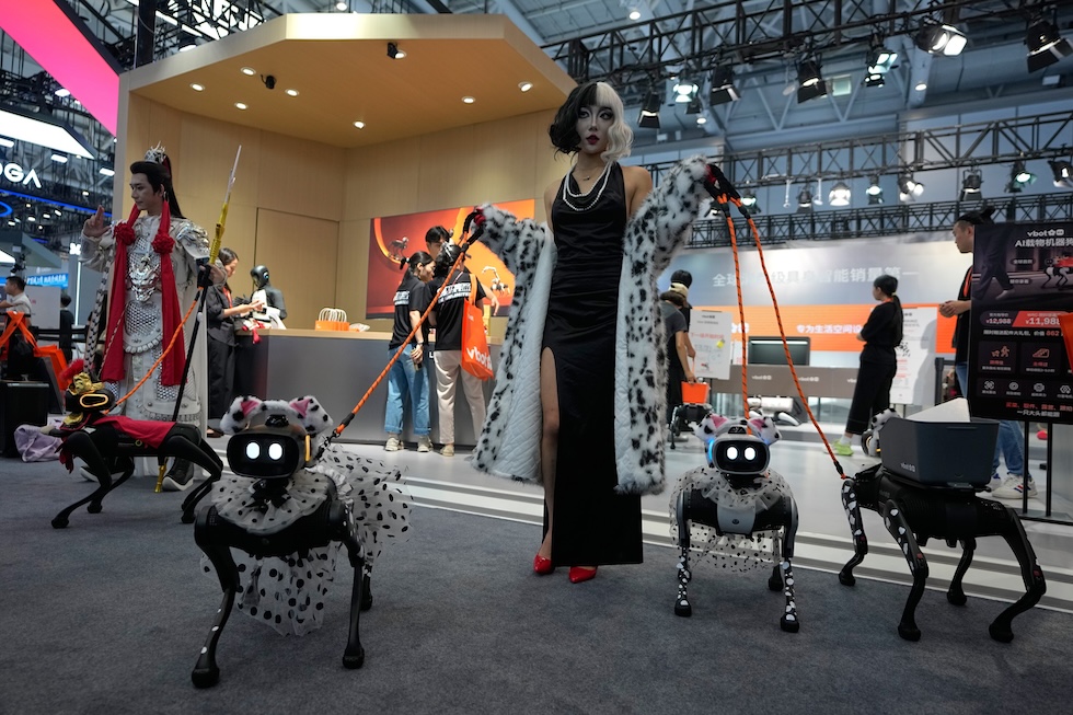 Una donna vestita da Crudelia De Mon mostra i suoi cani robotici, vestiti da dalmata, a uno stand della World Robot Conference, una conferenza internazionale dedicata alla robotica (AP Photo/Andy Wong)