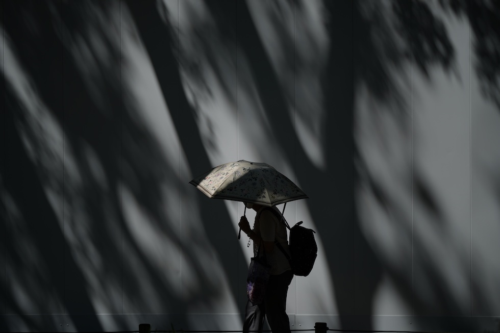 Una persona passeggia nel parco di Ueno riparandosi dal sole con un ombrello (AP Photo/Eugene Hoshiko)