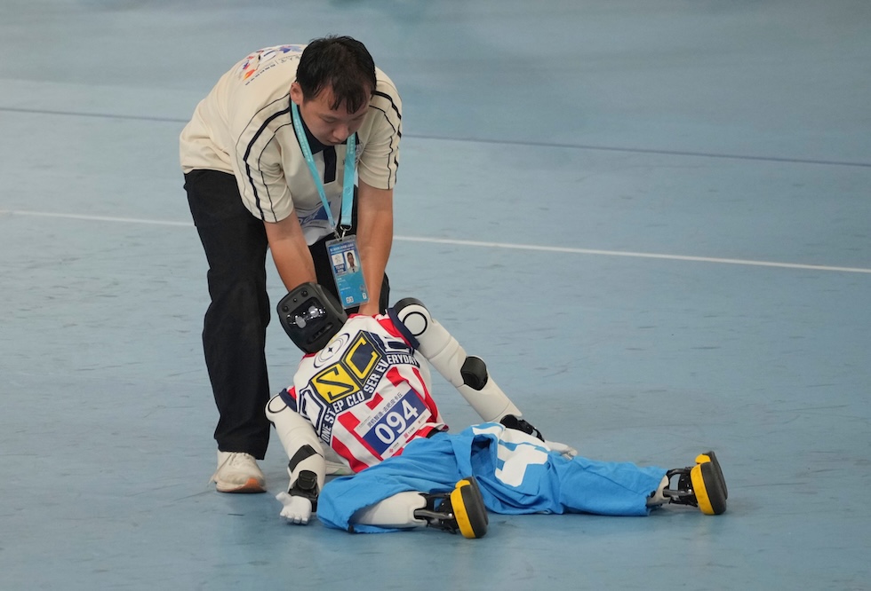 Un robot umanoide viene portato fuori dal campo dopo aver gareggiato nella breakdance ai World Humanoid Robot Games, i Giochi mondiali dei robot umanoidi (AP Photo/Achmad Ibrahim)