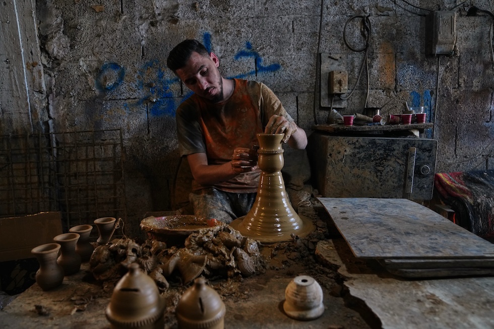 Un uomo usa un tornio da vasaio per realizzare vasi di argilla in un laboratorio di ceramica (AP Photo/Mahmoud Illean)