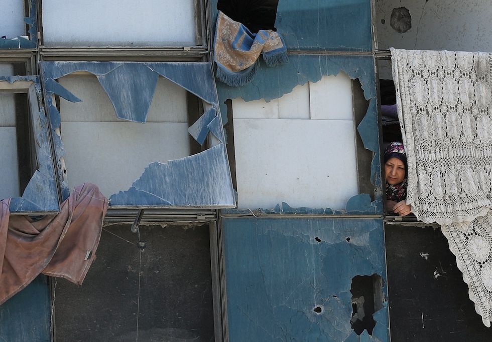 Una donna affacciata a un edificio danneggiato dell'ospedale al Shifa, durante il funerale di un palestinese ucciso dagli attacchi israeliani (REUTERS/Dawoud Abu Alkas)