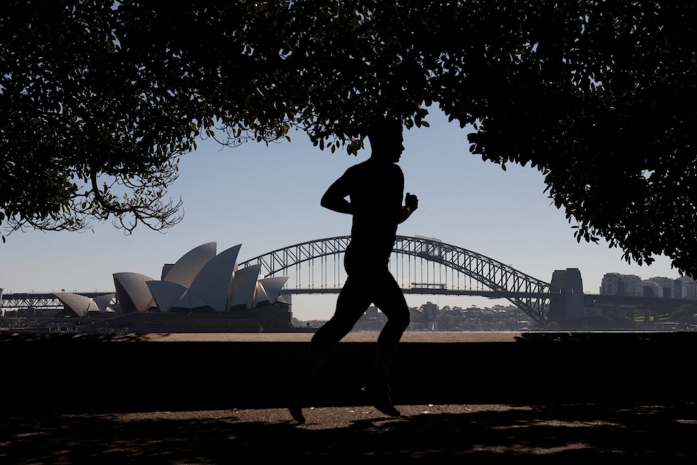 Un uomo fa jogging vicino all'Opera House e all'Harbour Bridge: gli australiani considerano oggi il primo giorno di primavera (REUTERS/Hollie Adams)