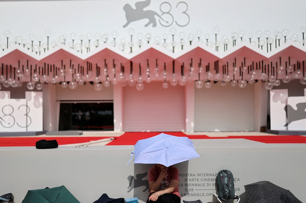 Una persona si ripara dal sole con un ombrello vicino al red carpet del festival del cinema di Venezia, che inizia domani (REUTERS/Yara Nardi)