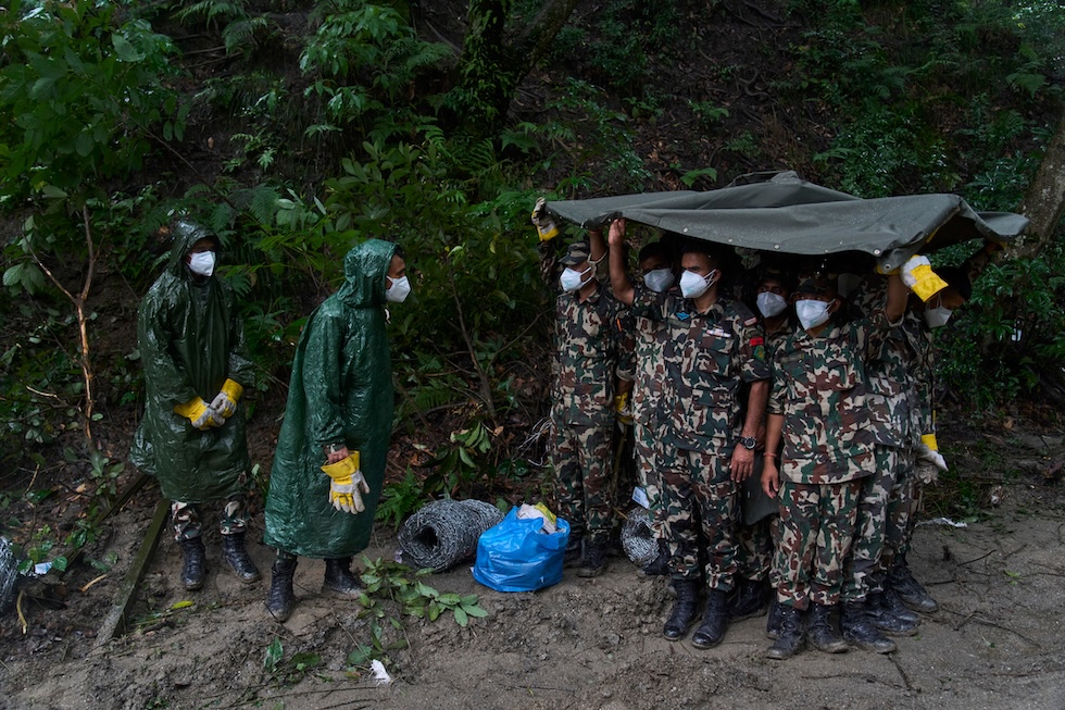Militari dell'esercito nepalese si riparano dalla pioggia mentre preparano il terreno per una sepoltura di massa delle persone morte a causa dell'esondazione della settimana scorsa (AP Photo/Niranjan Shrestha)