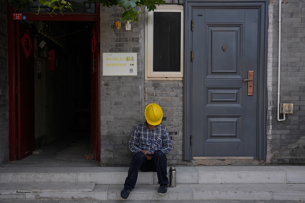 Un operaio riposa in un vicolo durante la pausa pranzo (AP Photo/Andy Wong)