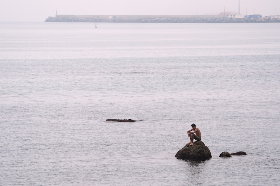 Un uomo seduto su uno scoglio sulla spiaggia di El Trampolín (AP Photo/Francis González)
