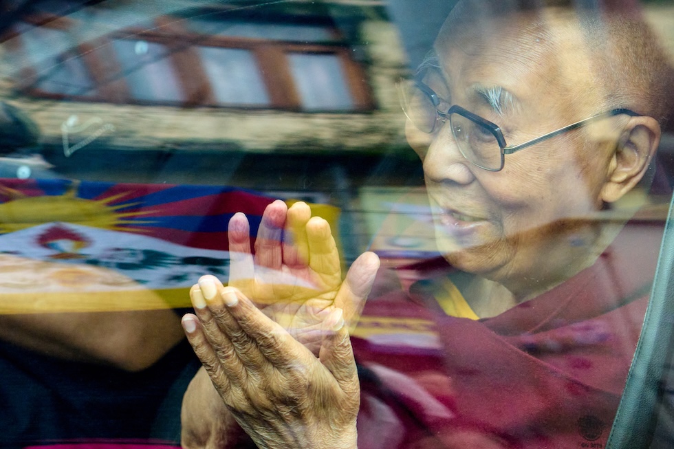 Il Dalai Lama saluta i fedeli dall'interno della sua auto (AP Photo/Ashwini Bhatia)
