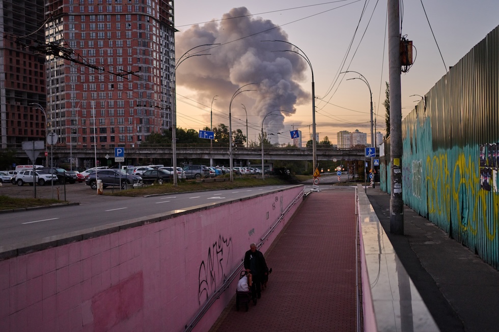 Un uomo in un sottopassaggio mentre sullo sfondo si vede una nube di fumo causata da un attacco missilistico russo (AP Photo/Francisco Seco)