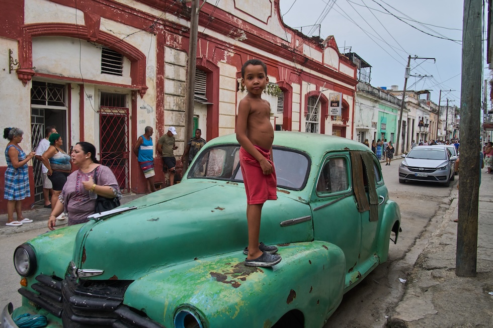 Un bambino in piedi su una vecchia auto americana in pessime condizioni (AP Photo/Ramon Espinosa)