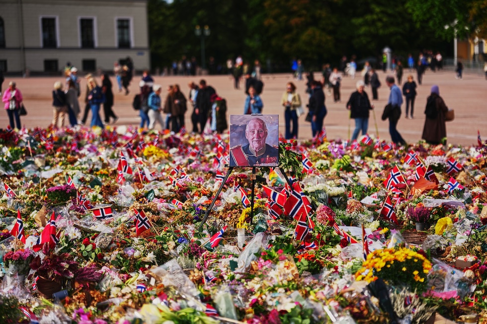 Un ritratto di re Harald di Norvegia, morto la settimana scorsa, tra gli omaggi floreali e le bandierine norvegesi nella piazza del palazzo reale (AP Photo/Markus Schreiber)