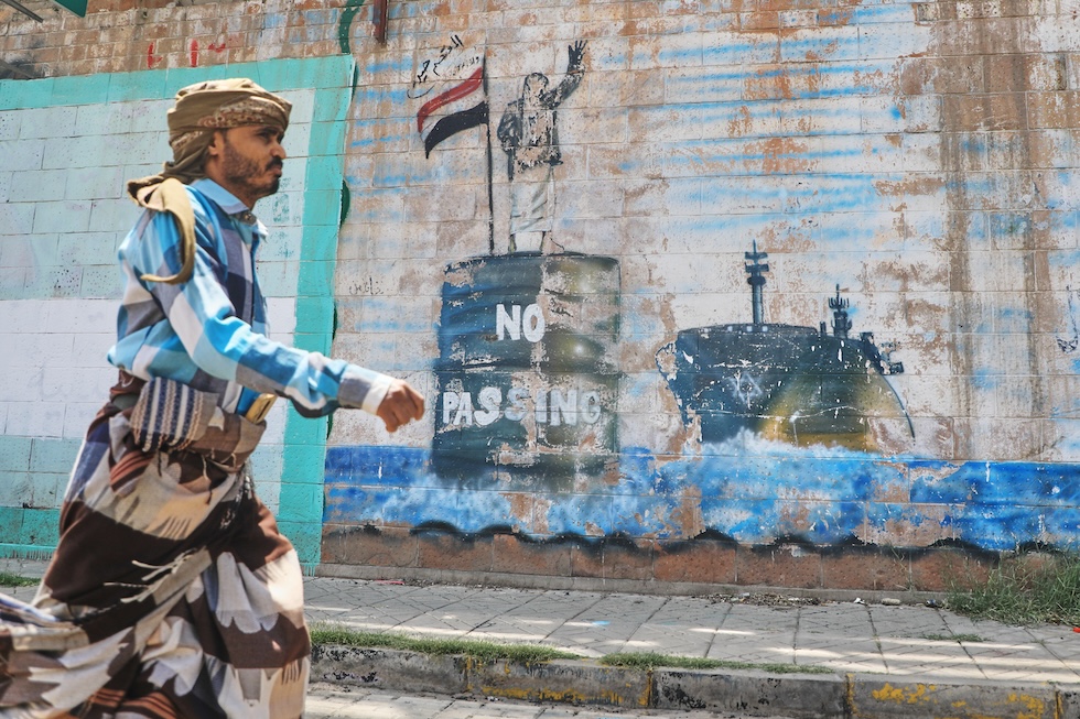 Un uomo davanti a un murale sullo stretto di Bab el Mandeb, uno dei punti nevralgici per il passaggio delle rotte petrolifere marittime mondiali (AP Photo/Osamah Abdulrahman)