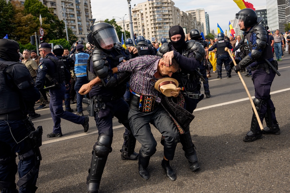 Un manifestante viene fermato dalla polizia durante una protesta degli agricoltori (AP Photo/Andreea Alexandru)