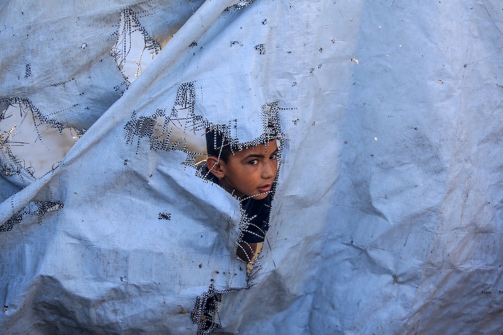 Un bambino sbuca da una delle tende che ospitano palestinesi sfollati, il giorno dopo un attacco israeliano all'accampamento  (Abed Rahim Khatib/Anadolu via Getty Images)
