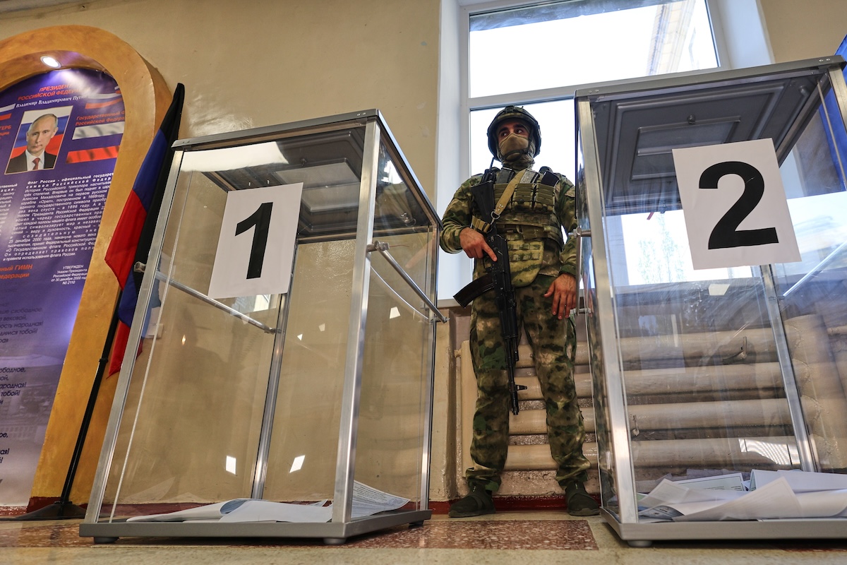 Un militare sorveglia alcune urne a Donetsk, nella regione ucraina di Donetsk occupata dalla Russia, il 18 settembre (AP Photo)