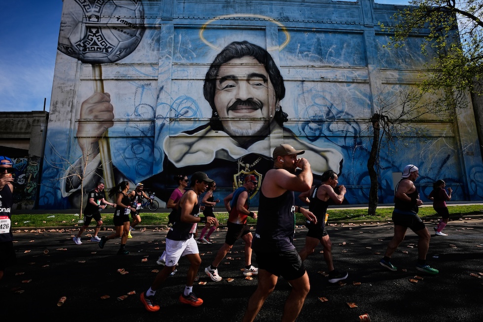 Partecipanti alla maratona davanti a un murale di Diego Maradona (AP Photo/Natacha Pisarenko)
