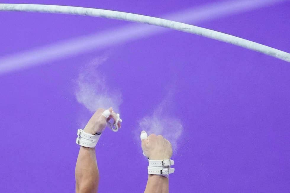 Le mani del giapponese Shinnosuke Oka, mentre cade durante l’esercizio alla sbarra orizzontale nella finale a squadre maschile di ginnastica artistica ai Giochi asiatici (AP Photo/Eugene Hoshiko)