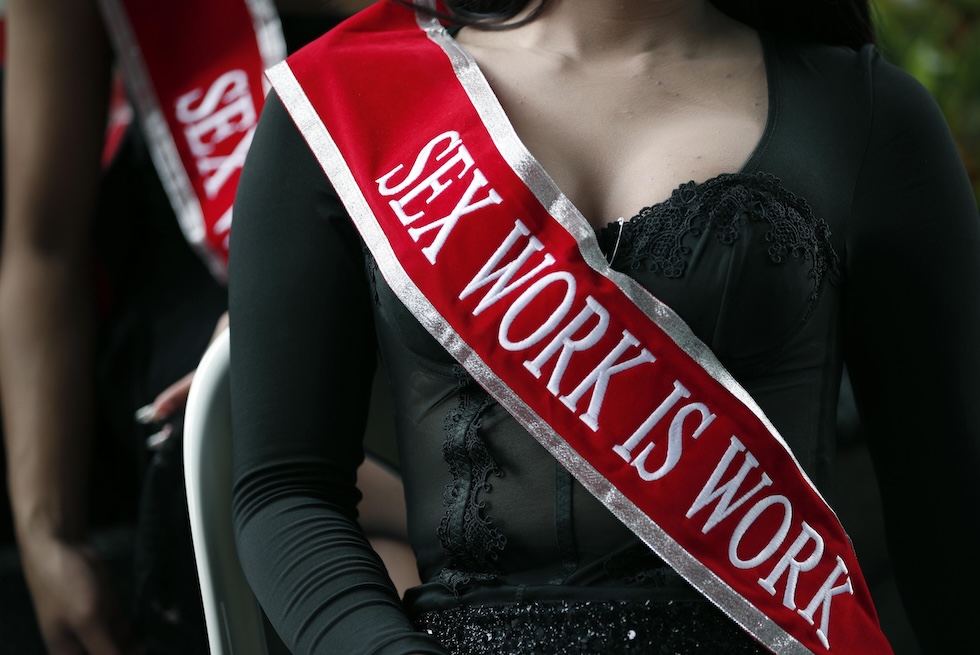 Alcune attiviste indossano una fascia con scritto «sex work is work» ("il lavoro sessuale è un lavoro") durante una manifestazione davanti al ministero dello Sviluppo sociale per chiedere l’approvazione di una legge che depenalizzi il lavoro sessuale (EPA/RUNGROJ YONGRIT)