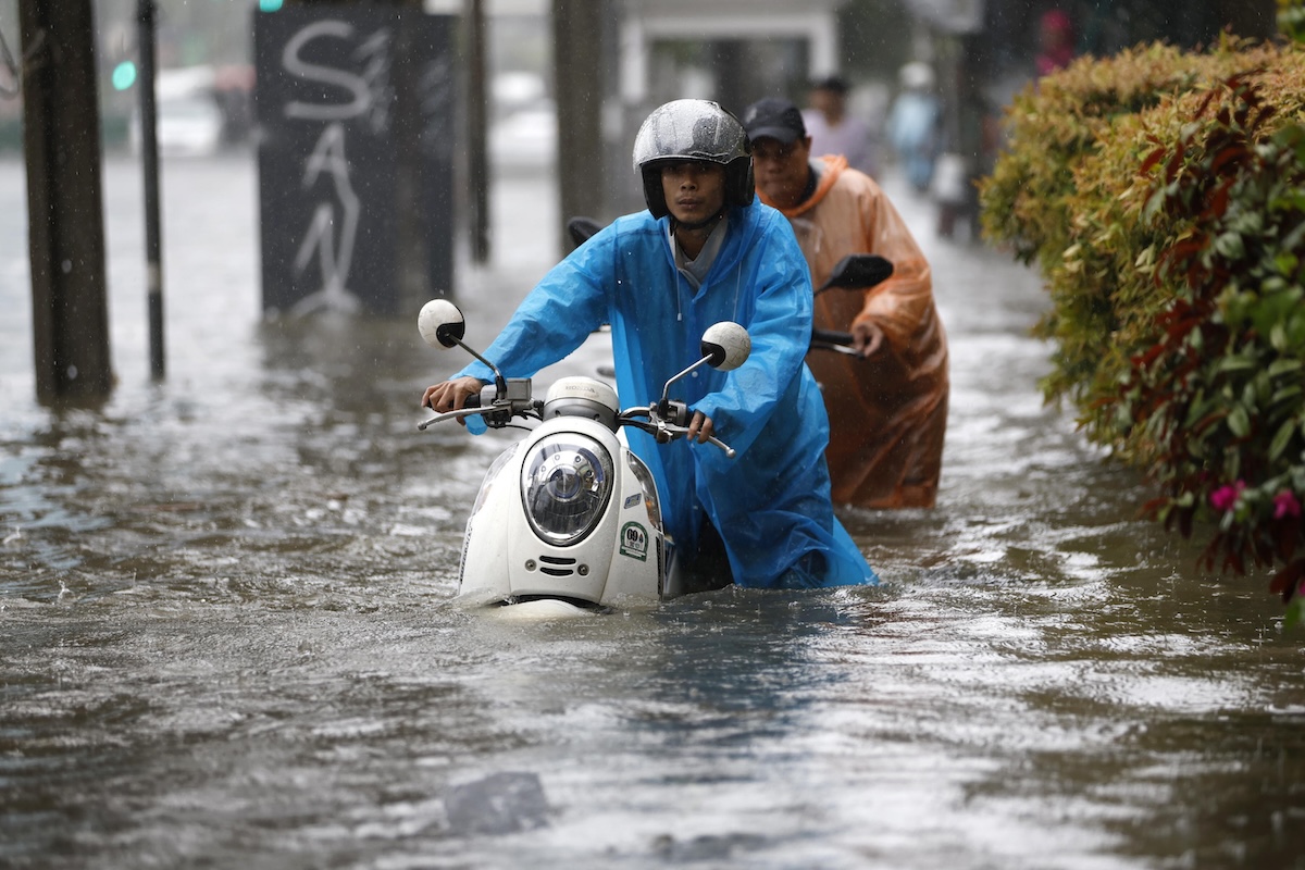 Alcuni uomini spingono i loro scooter nell'acqua su Phetchaburi Road (Rungoj Yongrit/Epa/ANSA)