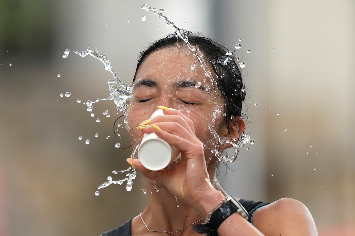Yasmina Toxanbayeva, atleta del Kazakistan, si rinfresca con un biscchiere d'acqua alla maratona di marcia femminile ai Giochi asiatici a Nagoya, in Giappone (AP Photo/Lee Jin-man)