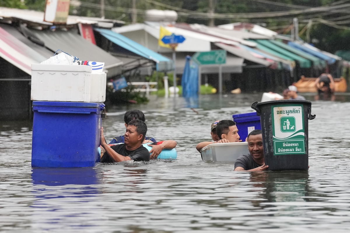 Persone che camminano nell'acqua alta dopo un'inondazione provocata dalle forti piogge a Bangkok, in Thailandia (AP Photo/Sakchai Lalit)