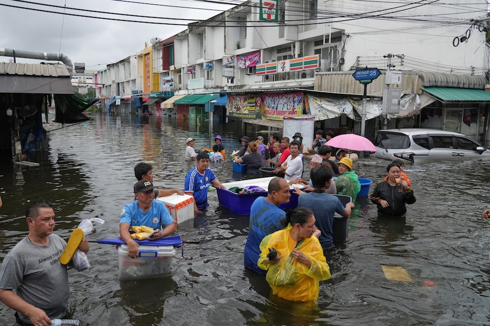Persone in una strada alluvionata a causa delle forti piogge (AP Photo/Sakchai Lalit)
