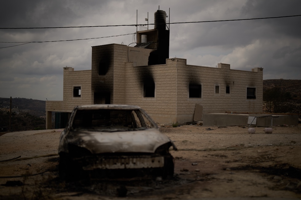 Un’auto bruciata davanti a una casa palestinese incendiata dai coloni israeliani  (AP Photo/Leo Correa)
