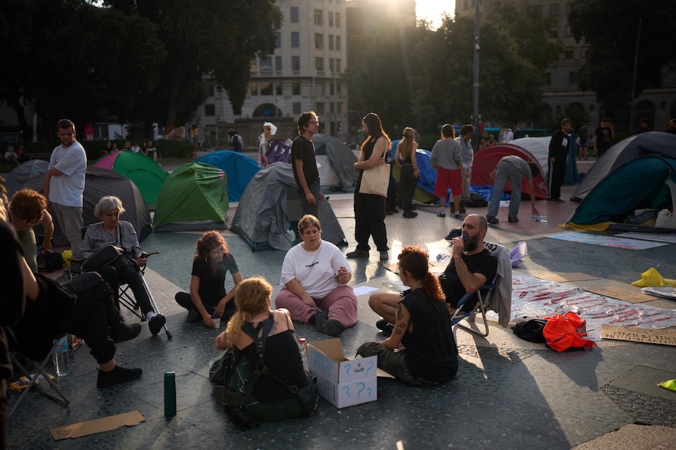 Manifestanti accanto alle loro tende dopo aver trascorso la notte accampati in Plaça de Catalunya (AP Photo/Emilio Morenatti)