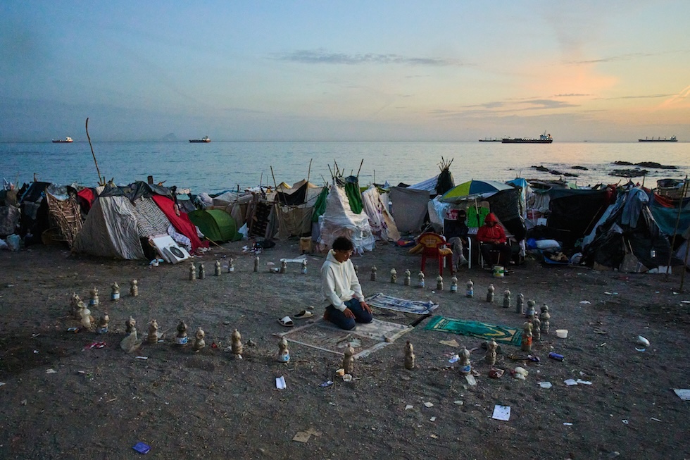 Un giovane arrivato dal Marocco prega al mattino sulla spiaggia di El Trampolín (AP Photo/Bernat Armangue)