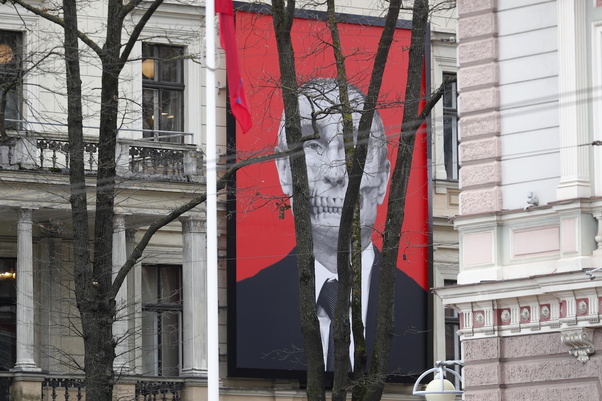 Un poster dove il presidente russo Vladimir Putin è raffigurato come personificazione della morte, sulla facciata di un museo dirimpetto all'ambasciata russa a Riga, in una foto del marzo 2024