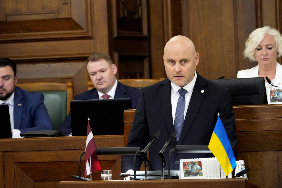Andris Kulbergs in parlamento il 28 maggio: sul podio dei discorsi, la bandiera lettone è affiancata da quella ucraina