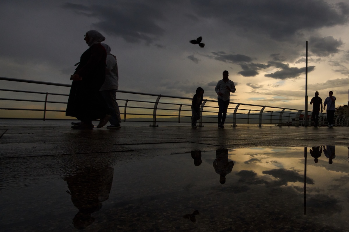 Alcune persone camminano sul lungomare dopo un acquazzone (AP Photo/Hassan Ammar)