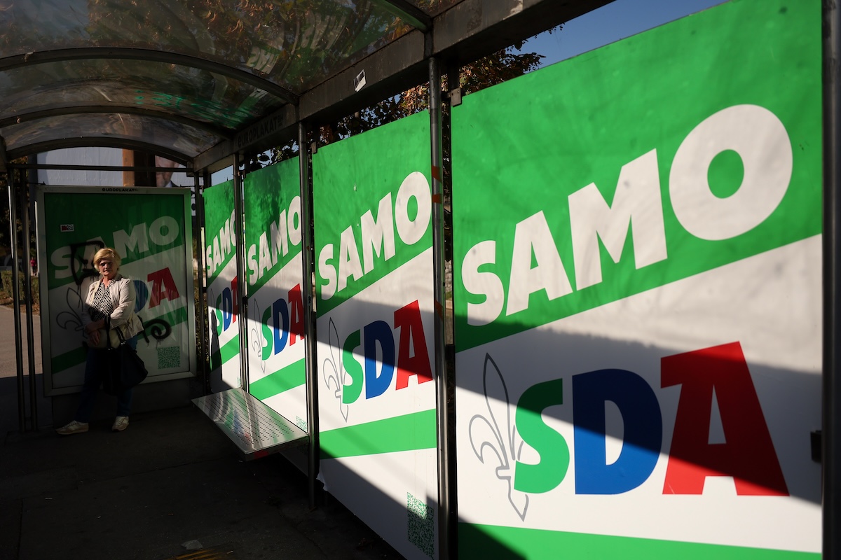 Una donna a una fermata del bus a Sarajevo ricoperta da poster elettorali dell'SDA (AP/Armin Durgut)