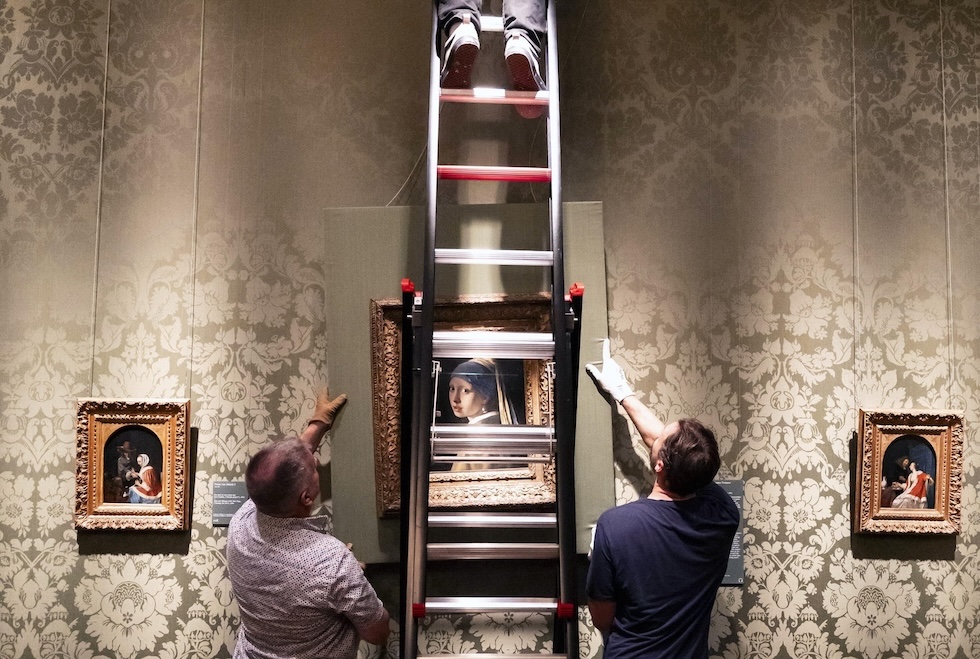 Personale del museo Mauritshuis appende il dipinto La ragazza con l'orecchino di perla, del pittore olandese Johannes Vermeer, rientrato al museo dopo un prestito in Giappone, dove era stato esposto a una mostra a Osaka (EPA/LINA SELG/ansa)