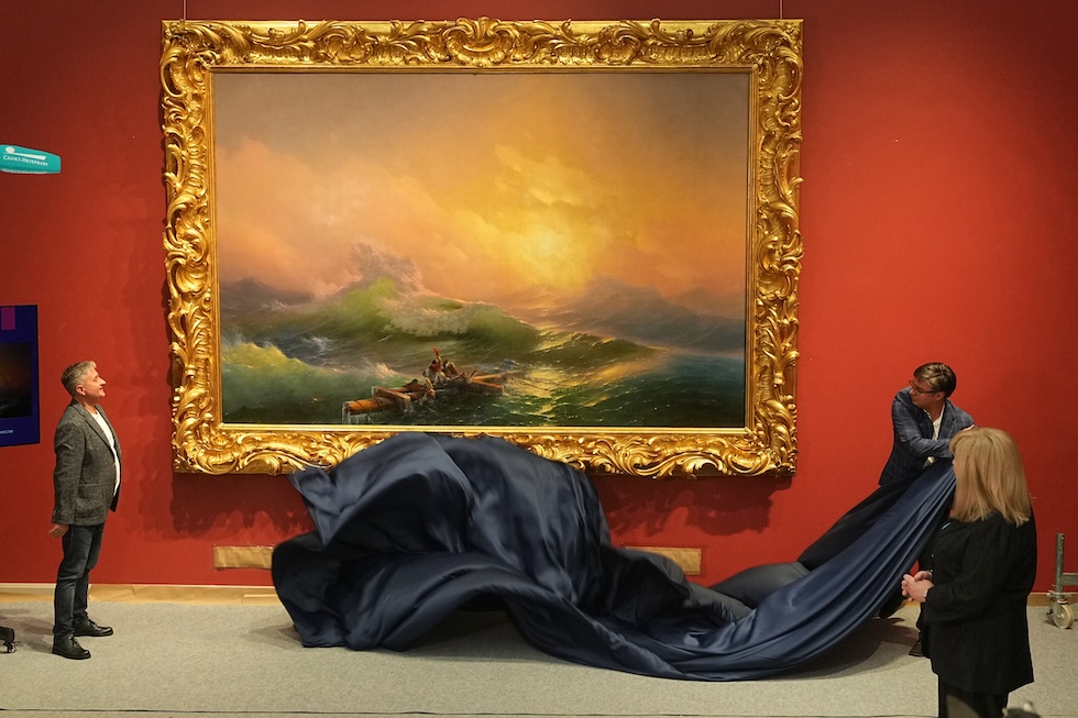 Un addetto scopre "La nona onda", dipinto del 1850 del pittore russo Ivan Ajvazovskij, dopo il suo restauro al Museo di Stato Russo (AP Photo/Dmitri Lovetsky)