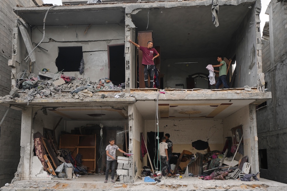 Persone palestinesi recuperano i propri effetti personali da un edificio distrutto nella notte da un attacco aereo israeliano (AP Photo/Jehad Alshrafi)
