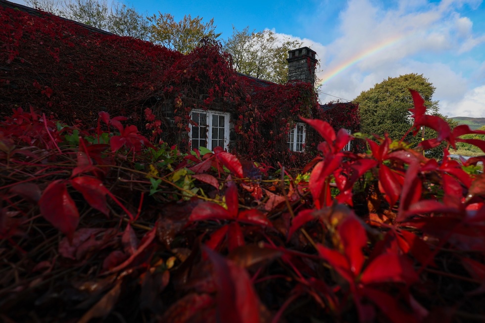 Un arcobaleno dietro la sala da tè Tu Hwnt i’r Bont, ricoperta di foglie autunnali (EPA/ADAM VAUGHAN via Ansa)