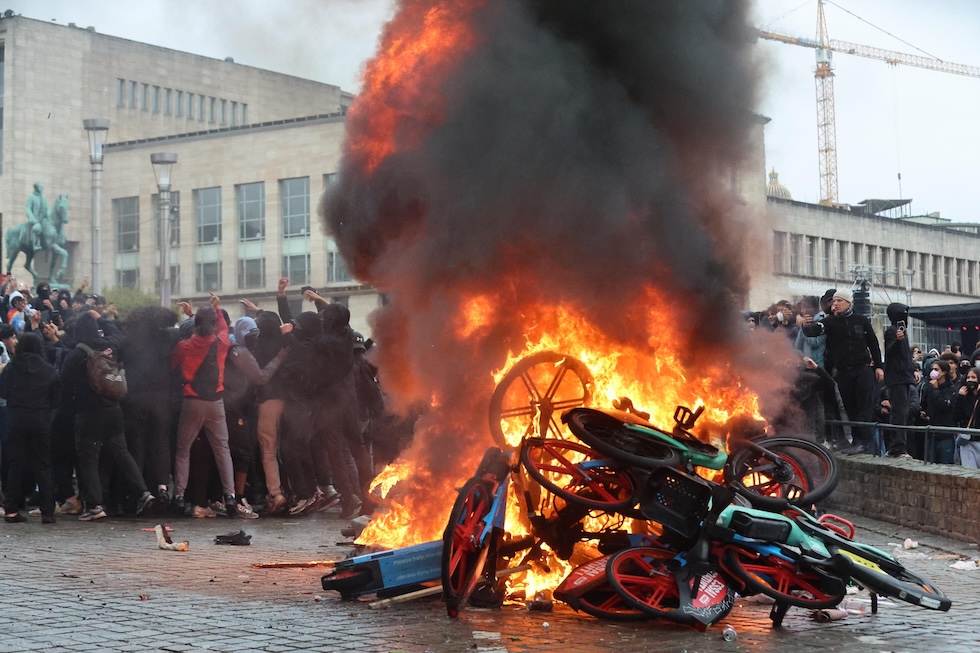 Manifestanti davanti a monopattini elettrici e biciclette in fiamme durante una protesta contro le riforme economiche e salariali previste dal governo federale belga (EPA/OLIVIER HOSLET via Ansa)